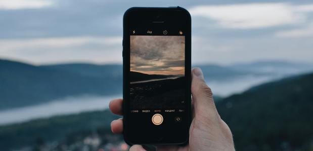 Iemand maakt met een smartphone een foto van een berglandschap