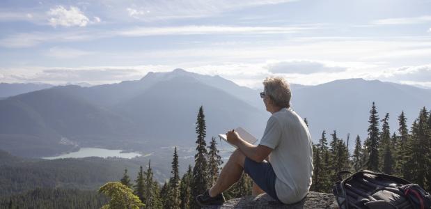 Man schrijft in een notitieboekje met uitzicht op de bergen