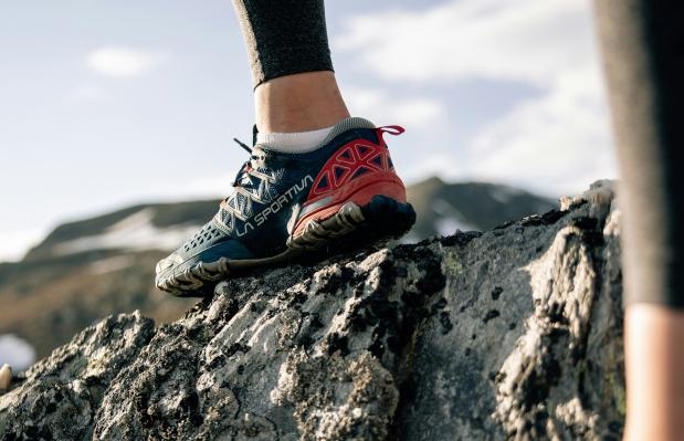 iemands voiet in een trailrunschoen op een rotsblok