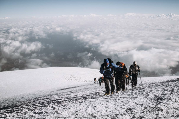 bergbeklimmers lopen door een besneeuwd landschap boven de wolken