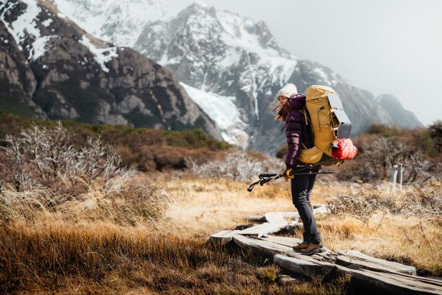 Als je veel bepakking bij je hebt, is het Aircontact Core systeem geschikt om je rugzak stabiel op je rug te houden. Foto Johannes Bitter vrouw met grote gele rugzak in een berglandschap